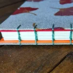 photo d'un carnet, modèle "ginkgo", vue sur la tranche et la reliure traditionnelle copte apparente, créations Endless Detours